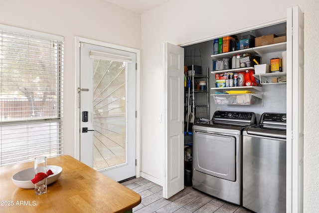 washroom featuring laundry area, washer and clothes dryer, a wealth of natural light, and wood tiled floor