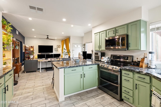 kitchen with a wealth of natural light, visible vents, green cabinets, appliances with stainless steel finishes, and a peninsula