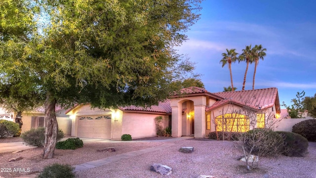 mediterranean / spanish house featuring concrete driveway, an attached garage, a tile roof, and stucco siding