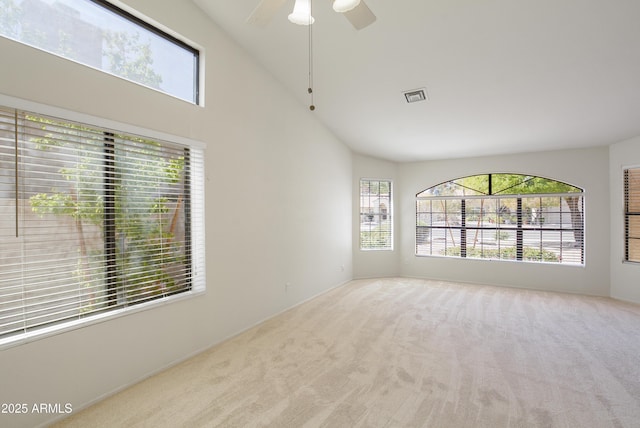 carpeted empty room featuring ceiling fan, high vaulted ceiling, visible vents, and a healthy amount of sunlight