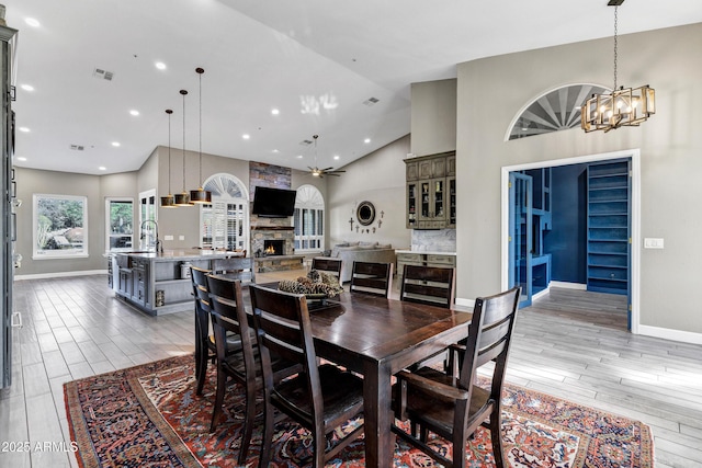 26475 N Wrangler Rd, Scottsdale, AZ 85255 - dining room with a chandelier, light wood-style floors, a stone fireplace, and high vaulted ceiling