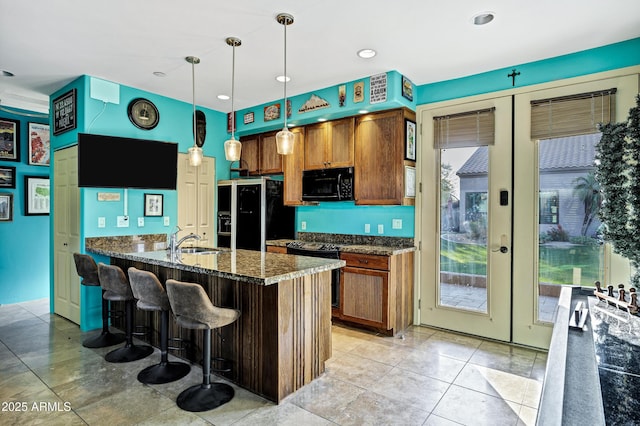 26475 N Wrangler Rd, Scottsdale, AZ 85255 - kitchen with black appliances, a peninsula, a kitchen bar, hanging light fixtures, and brown cabinetry