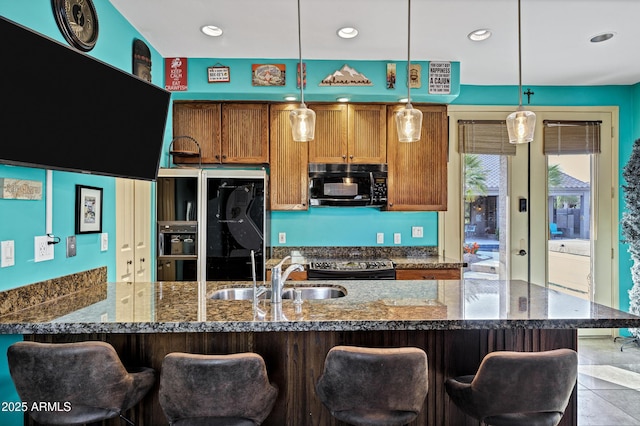 26475 N Wrangler Rd, Scottsdale, AZ 85255 - kitchen with black microwave, fridge with ice dispenser, pendant lighting, dark stone countertops, and a kitchen bar