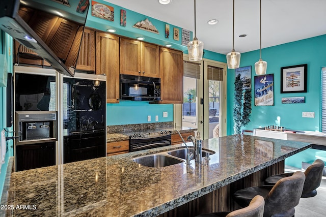 26475 N Wrangler Rd, Scottsdale, AZ 85255 - kitchen with black appliances, brown cabinets, hanging light fixtures, a kitchen breakfast bar, and dark stone countertops