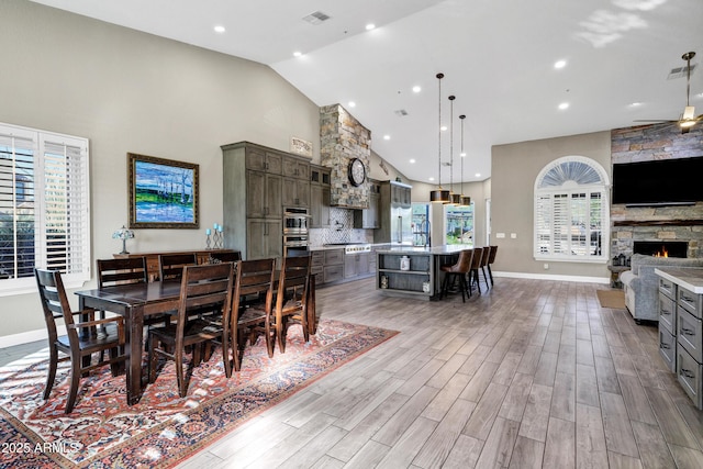 26475 N Wrangler Rd, Scottsdale, AZ 85255 - dining room with high vaulted ceiling, light wood finished floors, a ceiling fan, a fireplace, and recessed lighting