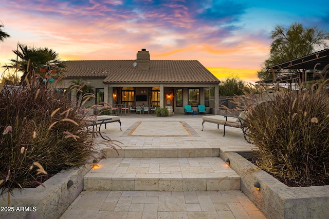 26475 N Wrangler Rd, Scottsdale, AZ 85255 - back of house at dusk with a chimney, a tile roof, a patio area, and stucco siding