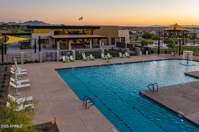 pool at dusk featuring pool water feature, exterior bar, a patio area, and a gazebo