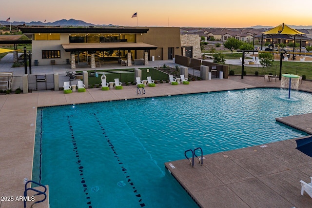 pool at dusk with a gazebo, a patio area, and pool water feature