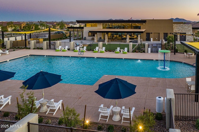 pool at dusk with a patio and pool water feature