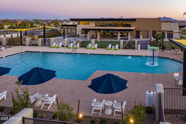 pool at dusk with a patio and pool water feature