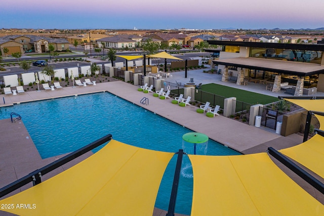 pool at dusk with a patio and exterior bar