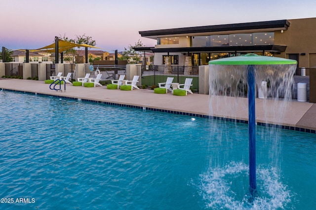 pool at dusk featuring pool water feature