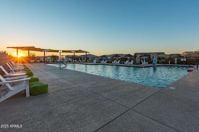 pool at dusk with a patio area