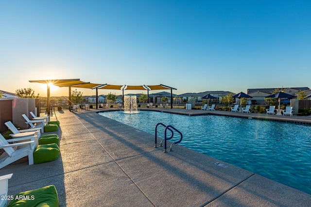 pool at dusk with pool water feature and a patio area