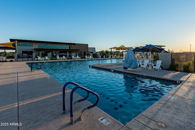 pool at dusk featuring a patio