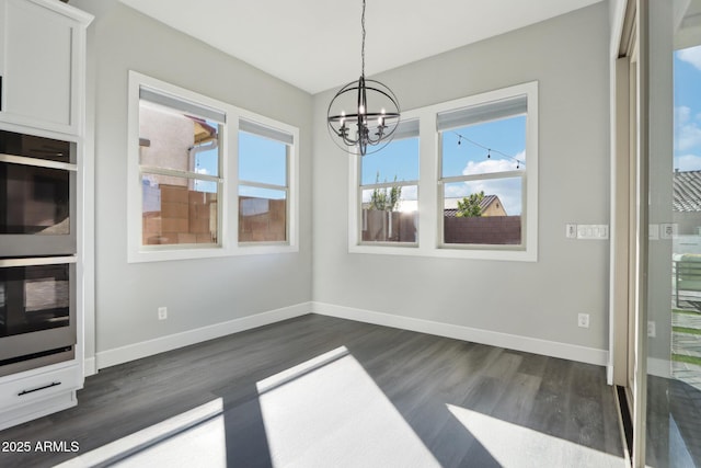 unfurnished dining area featuring an inviting chandelier and dark wood-type flooring