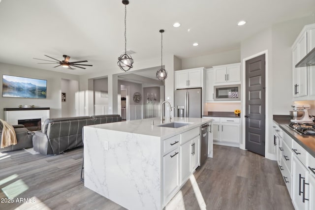 kitchen with white cabinetry, stainless steel appliances, a kitchen island with sink, and sink