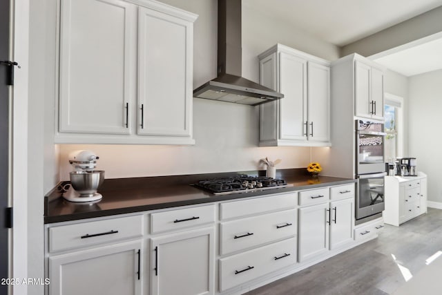 kitchen featuring stainless steel appliances, white cabinets, light wood-type flooring, and wall chimney exhaust hood