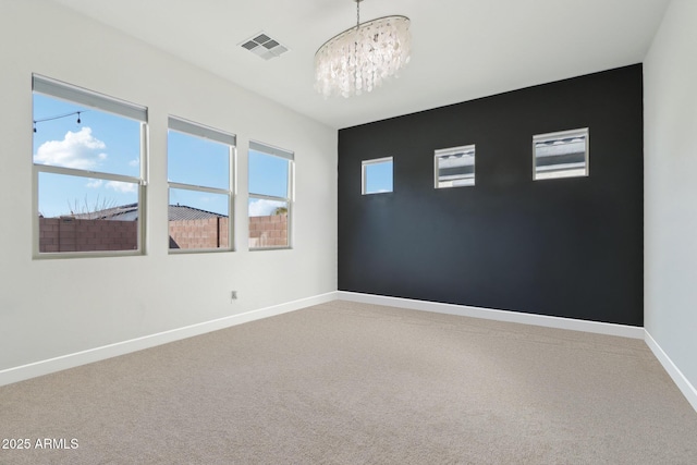 carpeted spare room with a notable chandelier