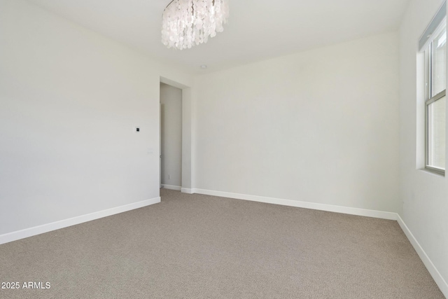 unfurnished room with a chandelier and carpet floors