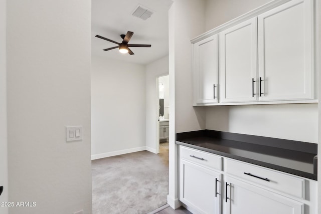 kitchen with light carpet, white cabinets, and ceiling fan