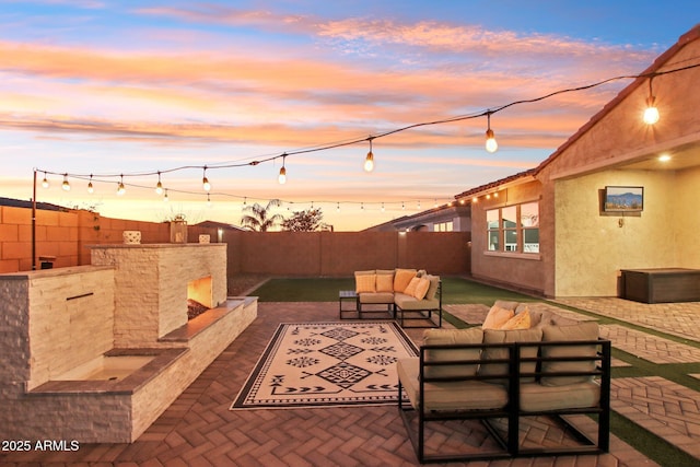 patio terrace at dusk featuring an outdoor living space with a fireplace