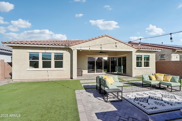 back of property featuring ceiling fan, outdoor lounge area, a patio area, and a lawn