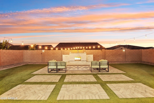 patio terrace at dusk featuring a lawn