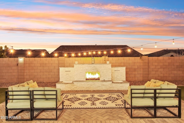 patio terrace at dusk featuring an outdoor living space with a fireplace