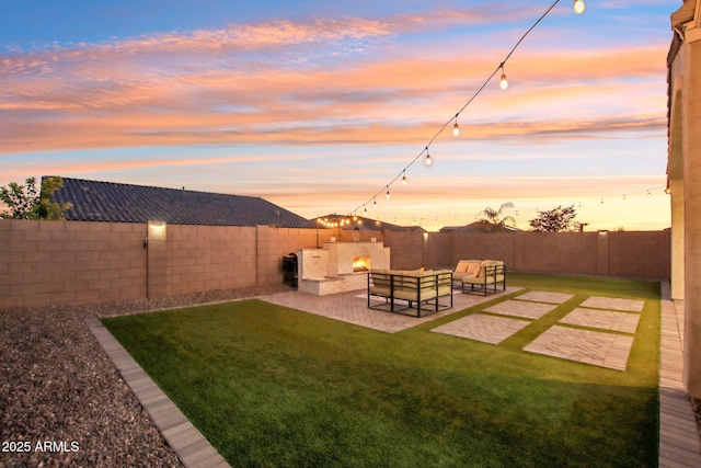 yard at dusk with an outdoor living space with a fireplace and a patio area