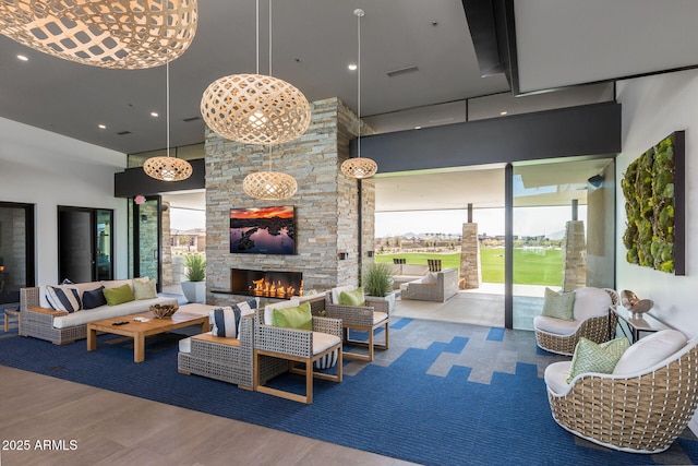 living room featuring a towering ceiling, hardwood / wood-style floors, and an outdoor stone fireplace