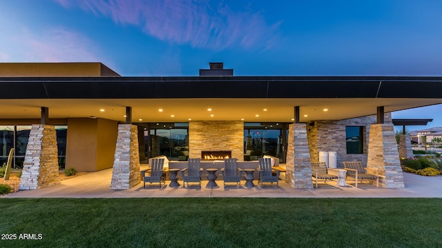 back house at dusk with a patio and a lawn