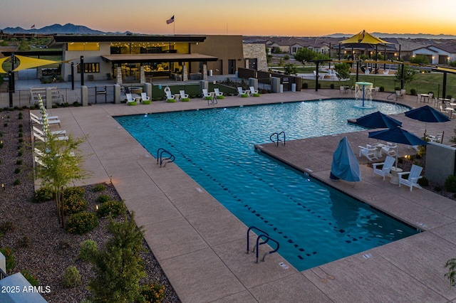 pool at dusk featuring a patio