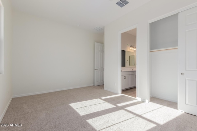 unfurnished bedroom with light carpet and connected bathroom