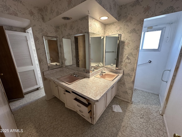 full bathroom featuring double vanity, a sink, and wallpapered walls