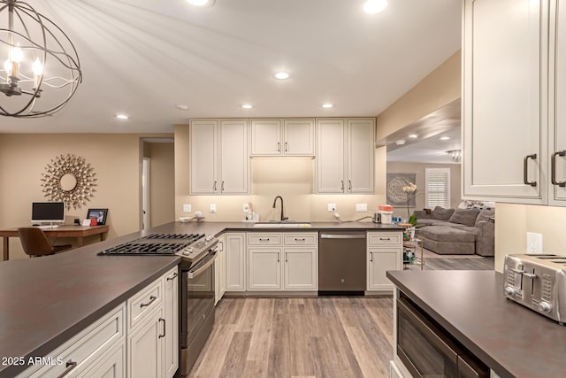 kitchen featuring an inviting chandelier, stainless steel appliances, light wood-type flooring, pendant lighting, and sink