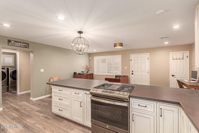 kitchen with gas stove, decorative light fixtures, white cabinetry, washing machine and clothes dryer, and a chandelier