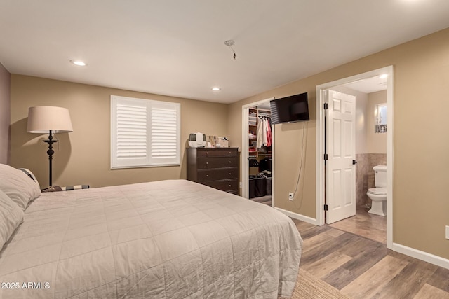 bedroom with light wood-type flooring, a closet, a walk in closet, and connected bathroom