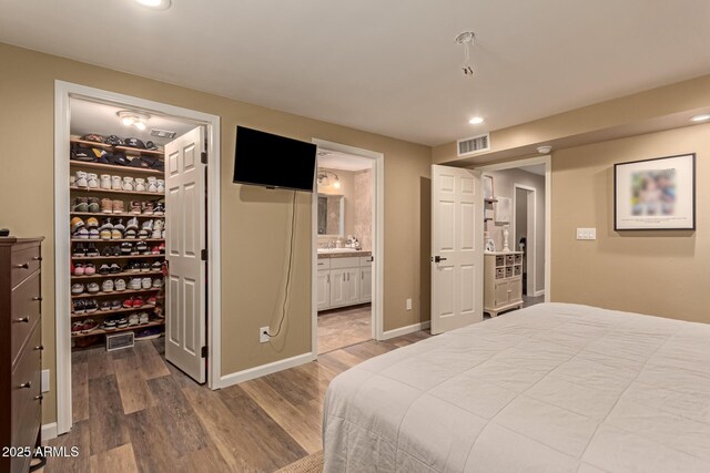 bedroom with sink, wood-type flooring, and connected bathroom