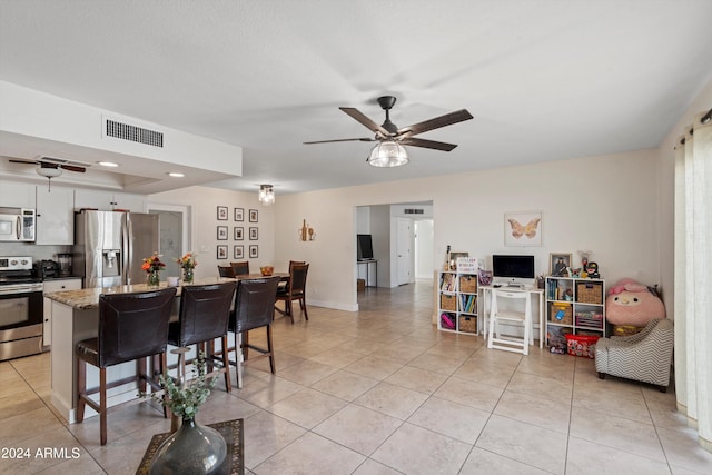 kitchen featuring a breakfast bar, light tile patterned floors, stainless steel appliances, and light stone counters