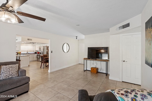 tiled living room with ceiling fan and a textured ceiling