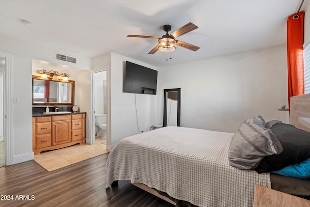 bedroom with multiple windows, ensuite bathroom, light hardwood / wood-style flooring, and ceiling fan