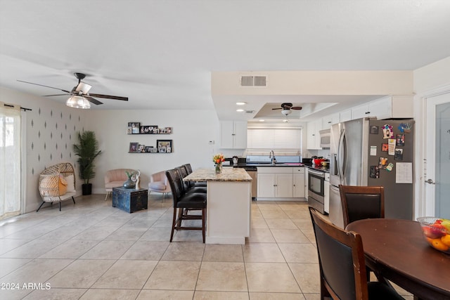 kitchen featuring a kitchen breakfast bar, white cabinetry, a center island, and stainless steel appliances