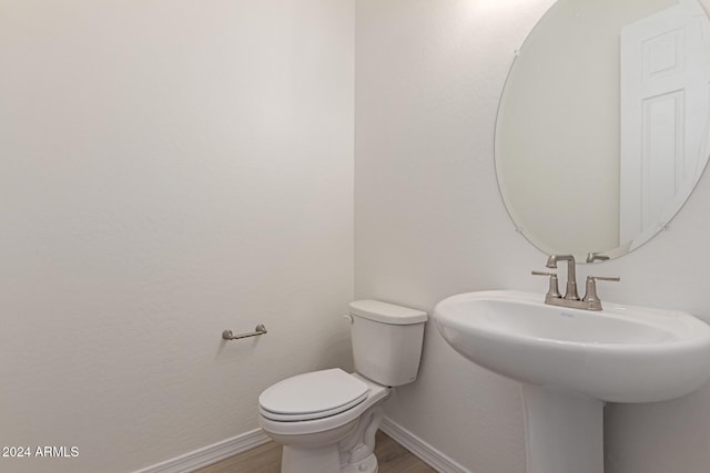 bathroom featuring wood-type flooring, toilet, and sink