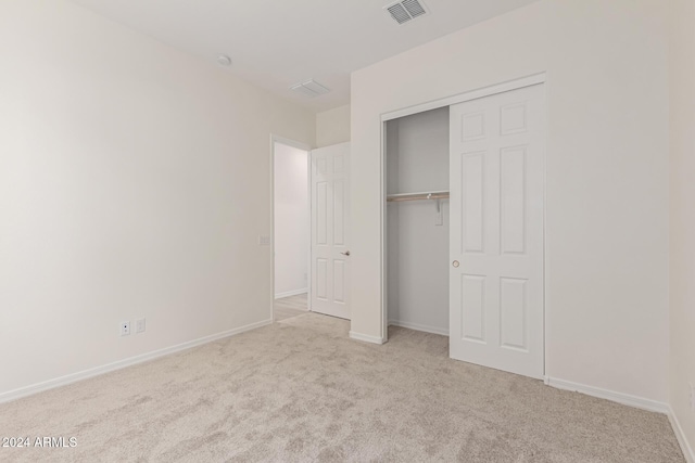 unfurnished bedroom featuring light carpet and a closet