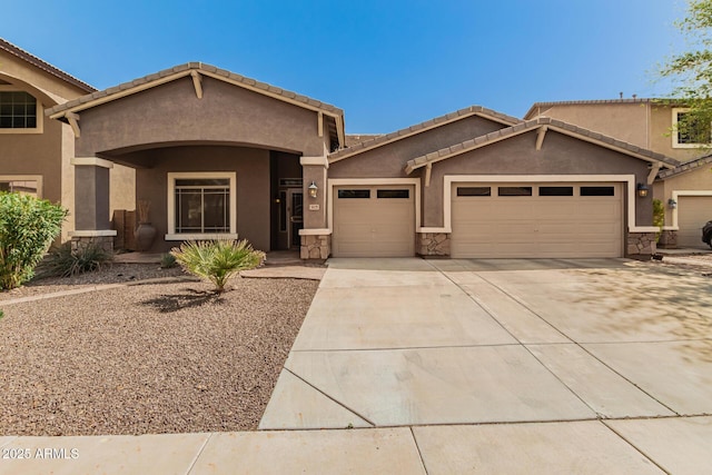 view of front of property with a tiled roof, an attached garage, driveway, and stucco siding