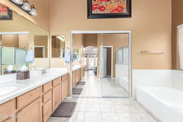 full bath featuring a garden tub, a stall shower, a sink, tile patterned flooring, and double vanity