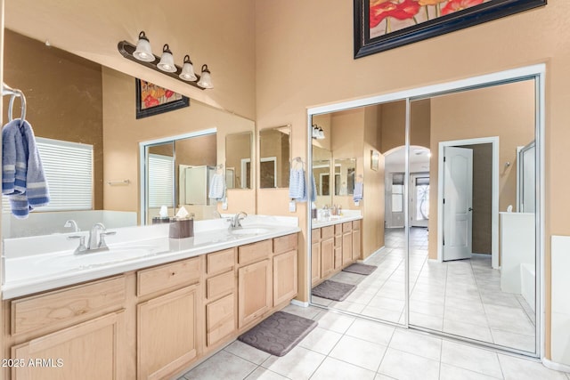 bathroom featuring tile patterned flooring, double vanity, a towering ceiling, and a sink