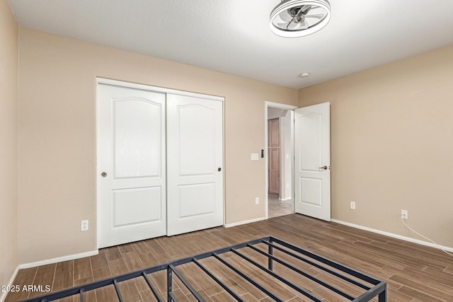 unfurnished bedroom with baseboards, a closet, and wood finish floors