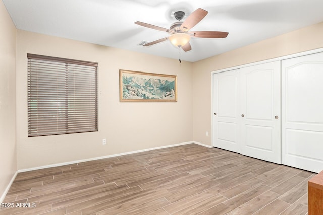 unfurnished bedroom with a closet, a ceiling fan, baseboards, and wood tiled floor